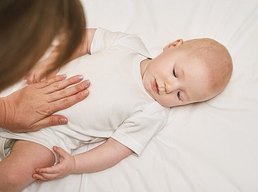 Frau legt Hand auf den Bauch eines Babys