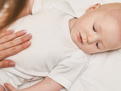 Frau legt Hand auf den Bauch eines Babys